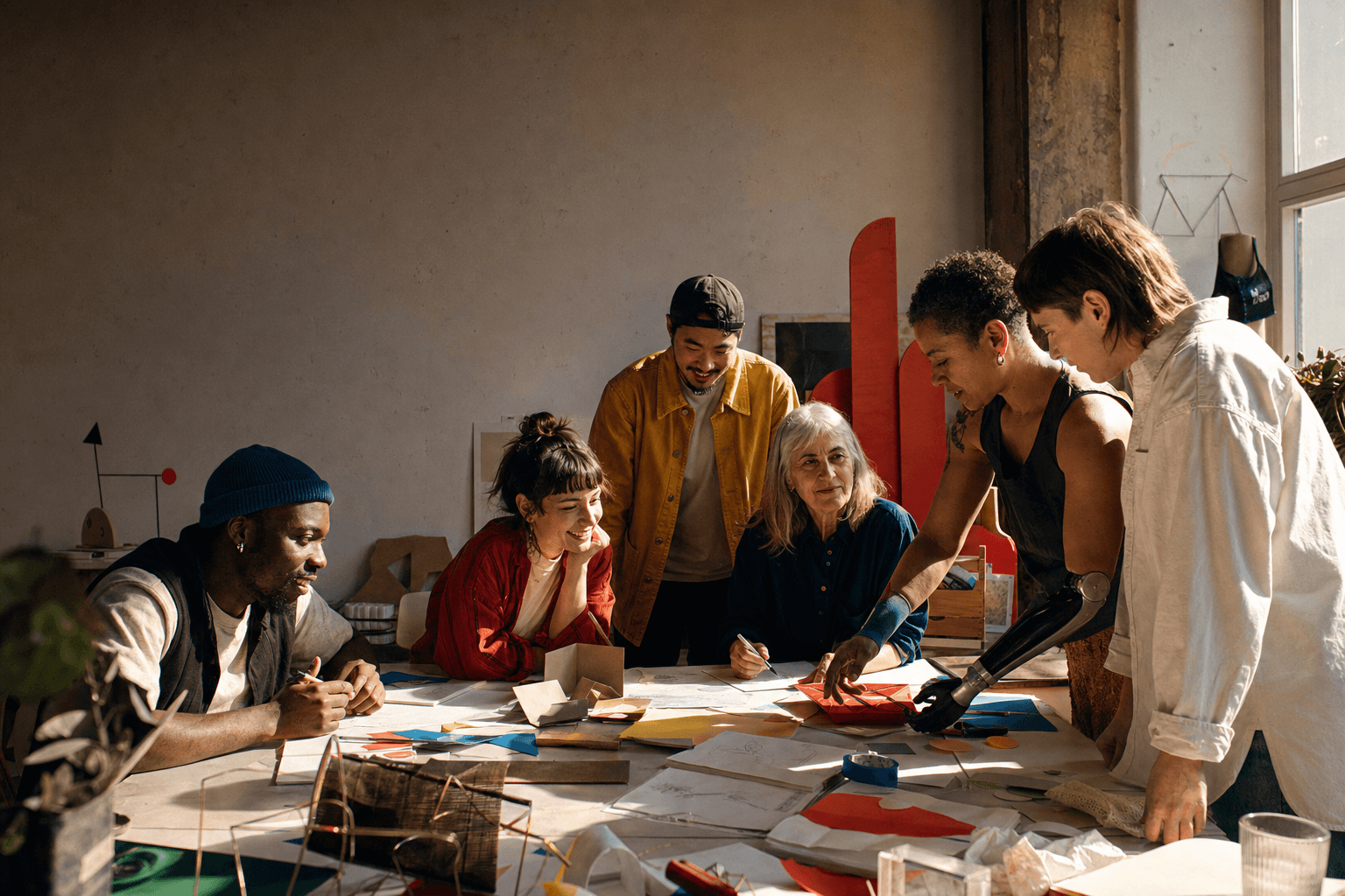 A diverse, cross-generational group of creative people building ideas together in a studio