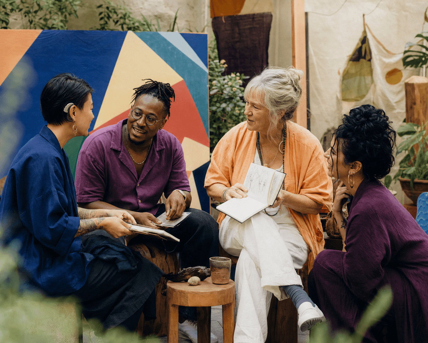 Four diverse creative people sharing sketchbooks and ideas in a gallery courtyard